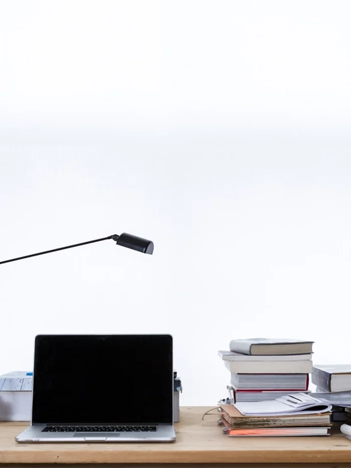 Laptop und Bücherstapel auf einem Schreibtisch